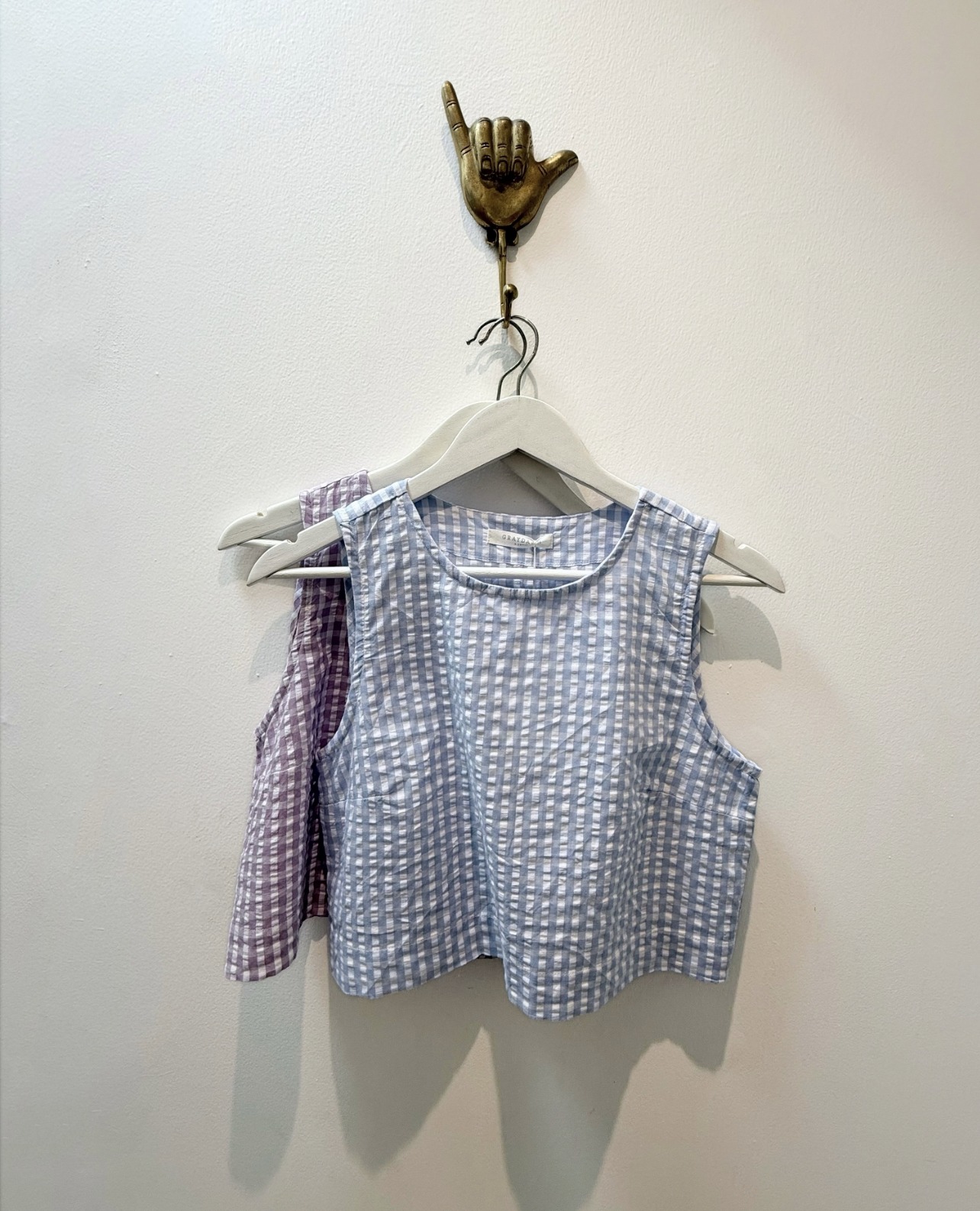 Gingham cotton top hanging on a brass hook in the boutique